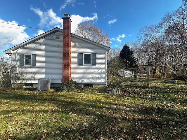 view of side of property with central AC unit and a lawn