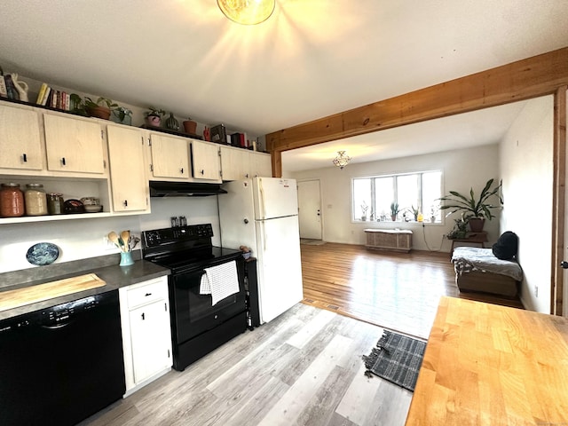 kitchen with beamed ceiling, light hardwood / wood-style floors, and black appliances