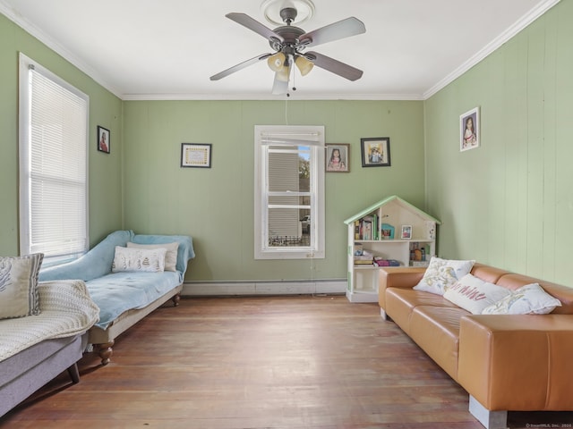 living room with ceiling fan, light hardwood / wood-style flooring, a baseboard heating unit, and ornamental molding