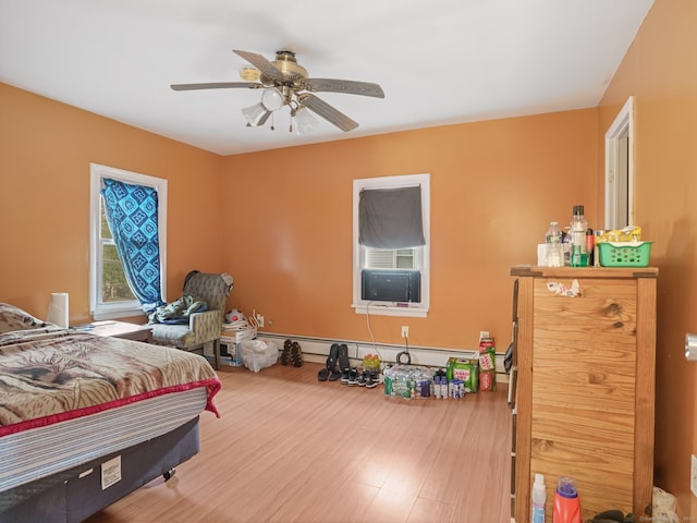 bedroom featuring hardwood / wood-style flooring, ceiling fan, and a baseboard radiator