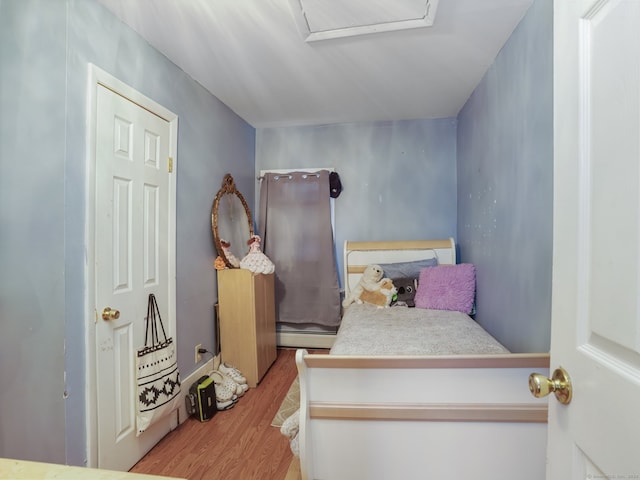 bedroom with baseboard heating and light hardwood / wood-style floors