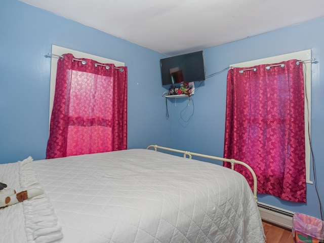 bedroom with baseboard heating and wood-type flooring