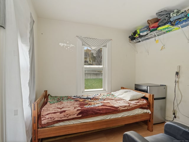 bedroom with stainless steel refrigerator and wood-type flooring