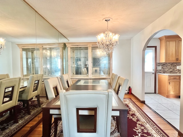 dining area featuring light hardwood / wood-style flooring, a textured ceiling, and an inviting chandelier