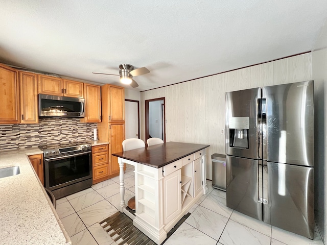 kitchen featuring a textured ceiling, ceiling fan, stainless steel appliances, and tasteful backsplash