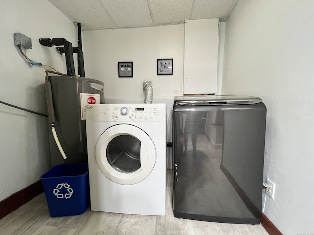 laundry area featuring washing machine and clothes dryer, water heater, and light hardwood / wood-style flooring