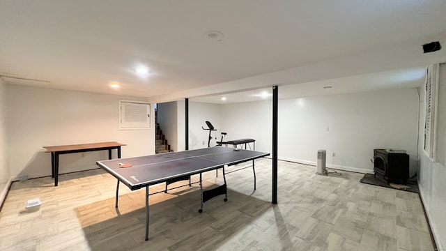 recreation room featuring light wood-type flooring and a wood stove