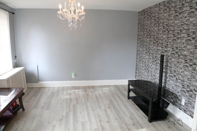 interior space featuring light wood-type flooring, radiator heating unit, and an inviting chandelier