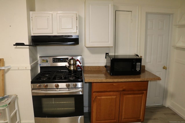 kitchen with white cabinets, hardwood / wood-style floors, exhaust hood, and gas stove