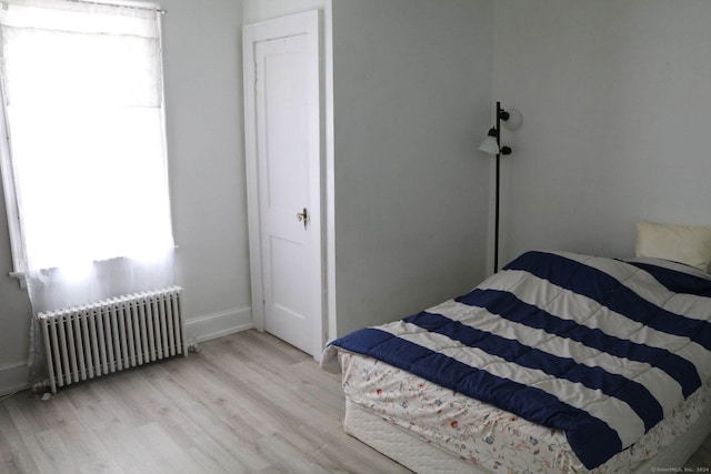 bedroom with radiator and light wood-type flooring