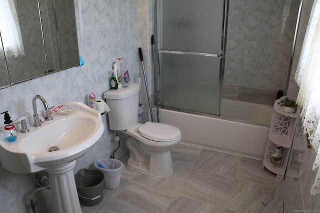 bathroom featuring combined bath / shower with glass door, toilet, and tile walls