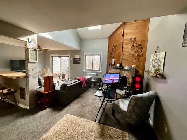 living room featuring ceiling fan, a stone fireplace, lofted ceiling, and carpet