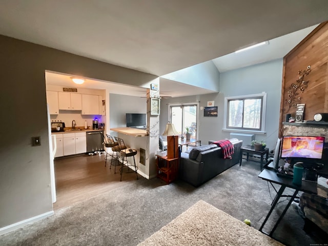 living room featuring a fireplace, ceiling fan, dark colored carpet, and sink