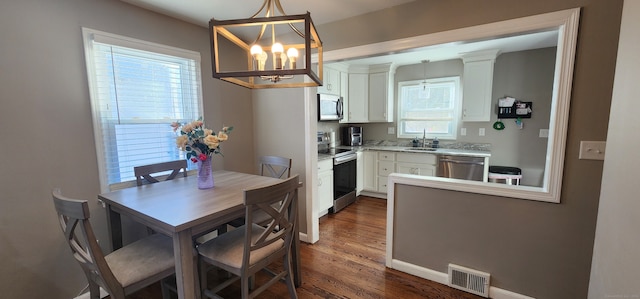 dining area with dark hardwood / wood-style floors, a healthy amount of sunlight, sink, and a chandelier