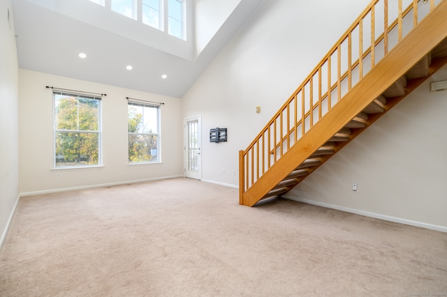 interior space with a high ceiling and light carpet