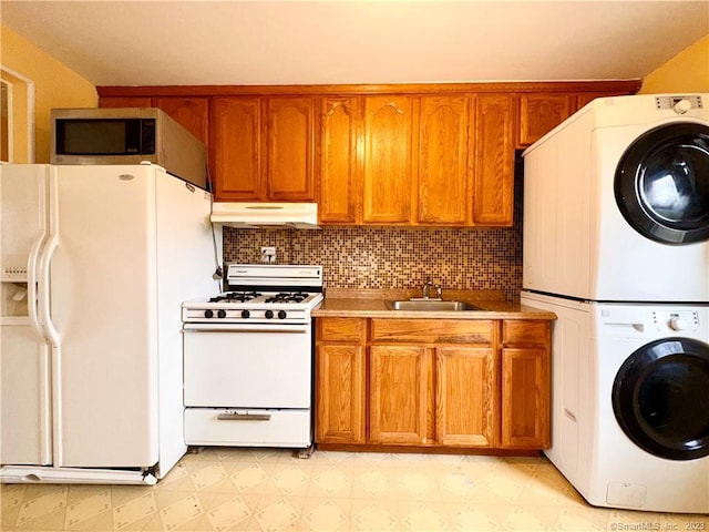 kitchen featuring white appliances, stacked washer and clothes dryer, sink, and decorative backsplash