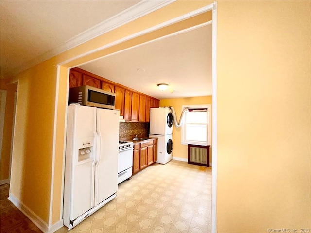 kitchen featuring stacked washer / dryer, tasteful backsplash, radiator heating unit, ornamental molding, and white appliances