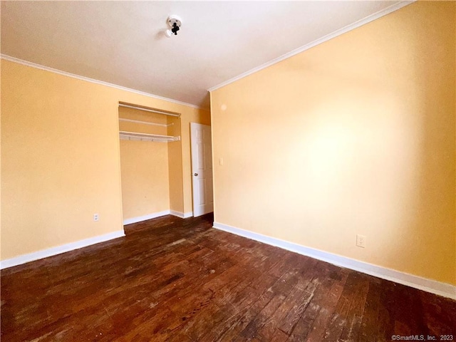 unfurnished bedroom with ornamental molding, dark wood-type flooring, and a closet