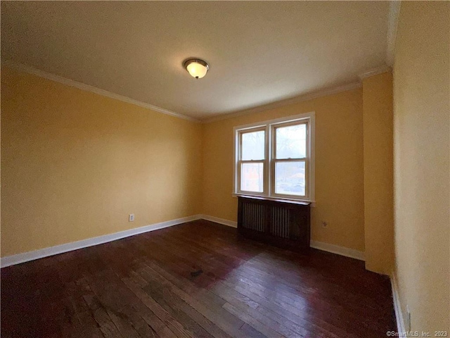 empty room with dark hardwood / wood-style floors, crown molding, and radiator