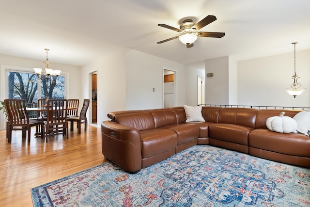 living room featuring ceiling fan with notable chandelier and light wood-type flooring