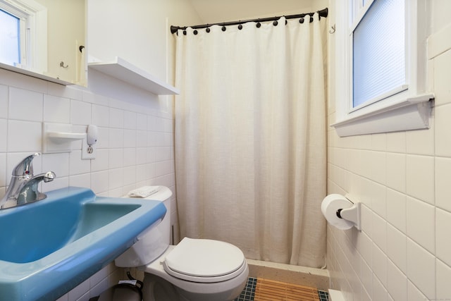 bathroom with a shower with shower curtain, toilet, sink, and tile walls