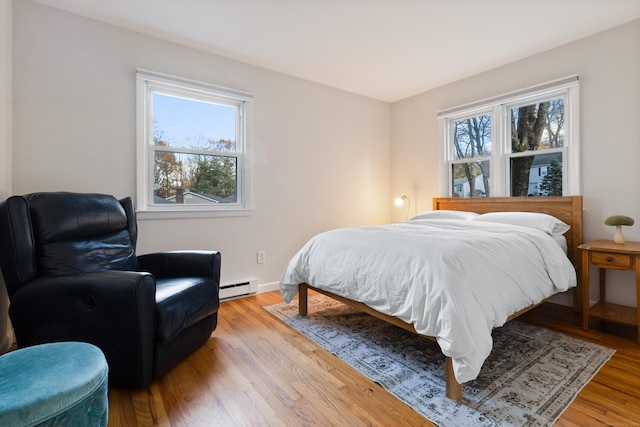 bedroom featuring a baseboard heating unit and light hardwood / wood-style flooring