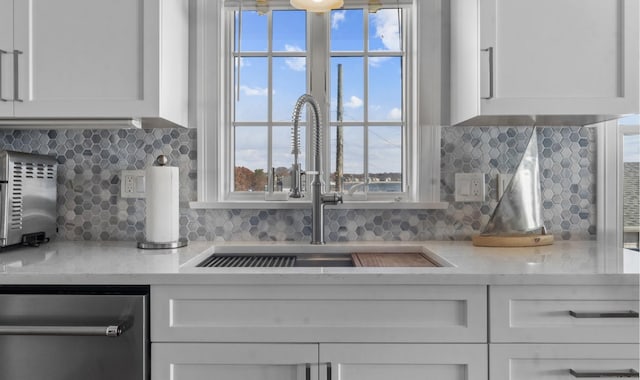442 Seaside Ave, Westbrook, CT 06498 - kitchen view of a sink, stainless steel dishwasher, white cabinetry, and backsplash