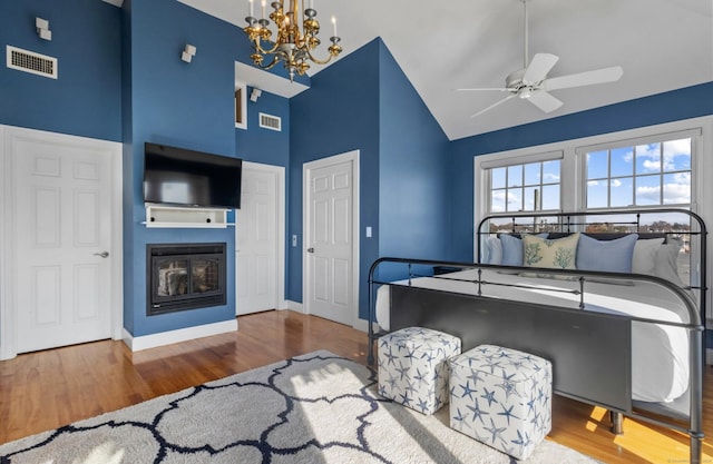 442 Seaside Ave, Westbrook, CT 06498 - bedroom with high vaulted ceiling, wood finished floors, a chandelier, a glass covered fireplace, and baseboards