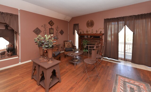 living room featuring a brick fireplace, light hardwood / wood-style floors, and lofted ceiling