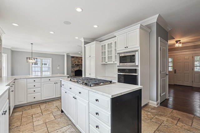 kitchen featuring white cabinets, pendant lighting, appliances with stainless steel finishes, and a center island