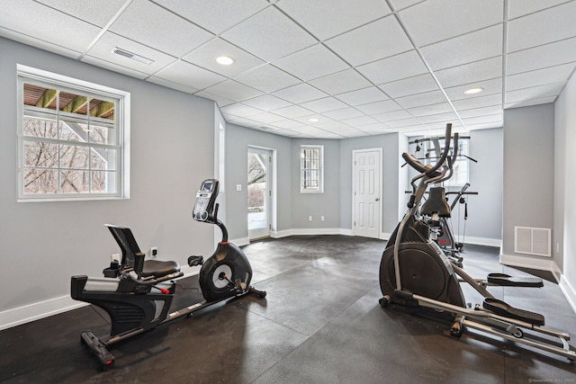 workout room featuring a healthy amount of sunlight and a drop ceiling