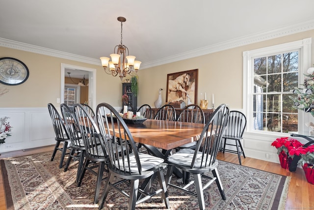 dining space with ornamental molding, light hardwood / wood-style floors, and an inviting chandelier