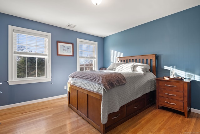 bedroom with multiple windows and light hardwood / wood-style flooring