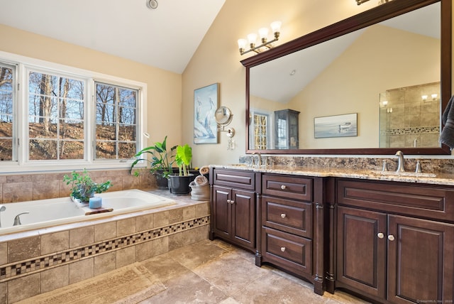 bathroom featuring lofted ceiling, a relaxing tiled tub, tile patterned floors, and vanity