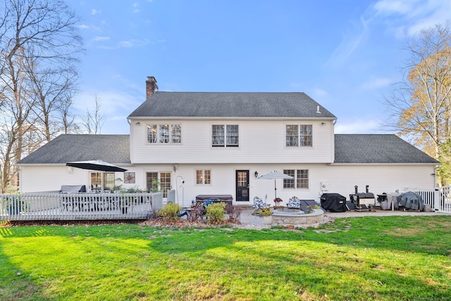 rear view of property featuring a lawn, a wooden deck, and a patio area