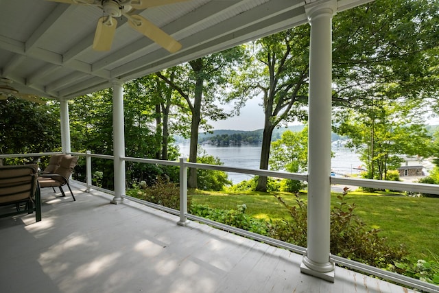 unfurnished sunroom with a ceiling fan and a water view