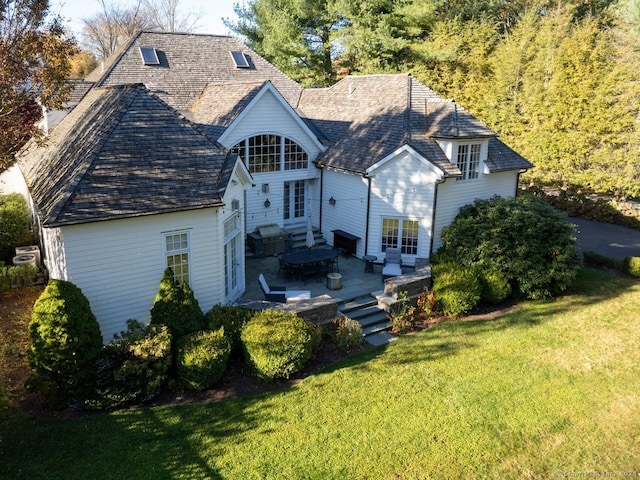 back of property with a yard and a patio area