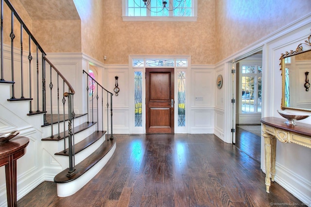 foyer entrance featuring a towering ceiling and dark wood-type flooring