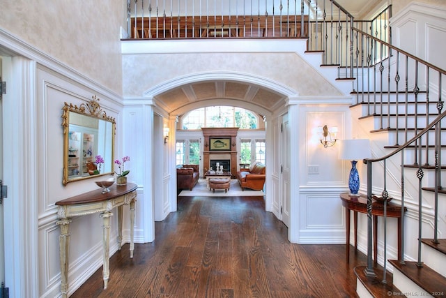 entryway featuring decorative columns, dark wood-type flooring, and a high ceiling