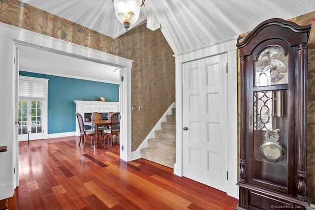 foyer entrance featuring hardwood / wood-style floors, lofted ceiling, and crown molding