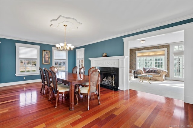 dining area featuring wood-type flooring, a notable chandelier, a healthy amount of sunlight, and crown molding