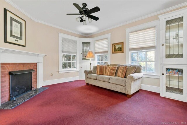 living room with ceiling fan, carpet, a brick fireplace, and crown molding