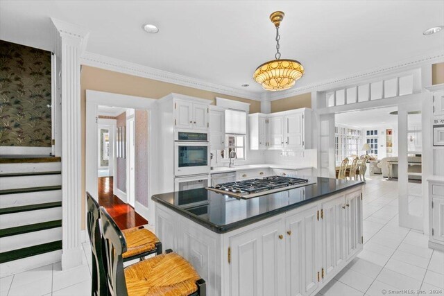 kitchen featuring white cabinets, stainless steel gas cooktop, white double oven, and crown molding