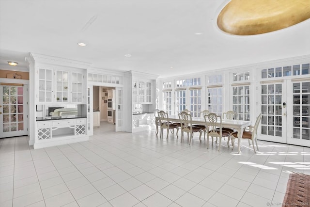 unfurnished dining area featuring light tile patterned flooring, french doors, and crown molding