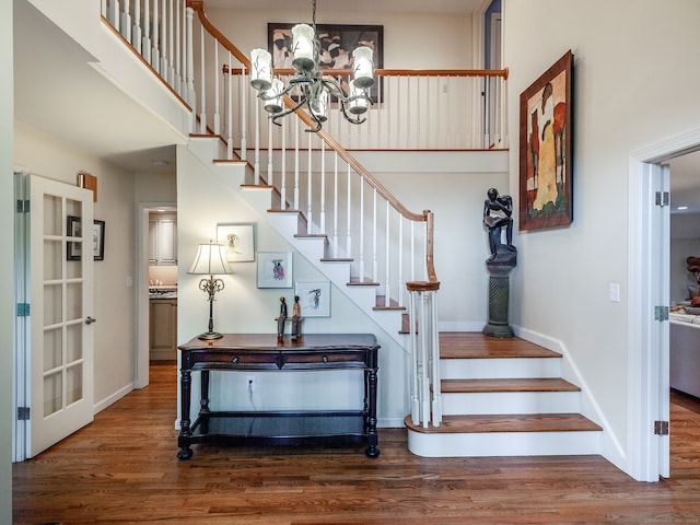 stairway with hardwood / wood-style floors and an inviting chandelier