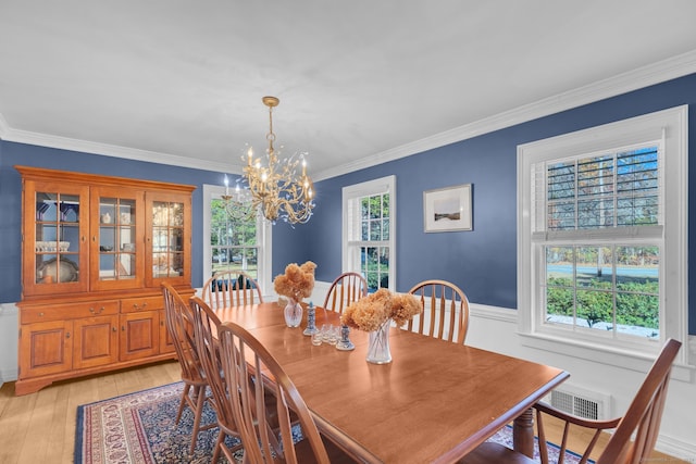 dining area with light hardwood / wood-style floors, a chandelier, and ornamental molding