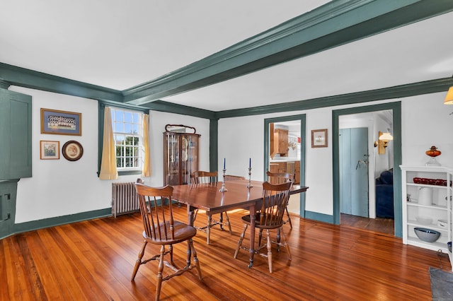 dining area featuring beamed ceiling, radiator heating unit, hardwood / wood-style flooring, and crown molding