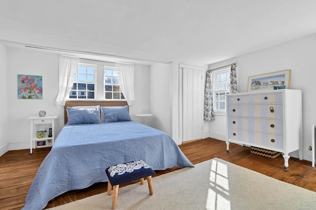 bedroom with multiple windows and dark hardwood / wood-style flooring