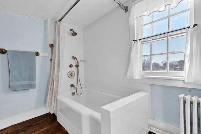 bathroom featuring hardwood / wood-style floors, shower / bathtub combination with curtain, and radiator