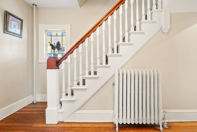 stairway featuring radiator heating unit and hardwood / wood-style flooring